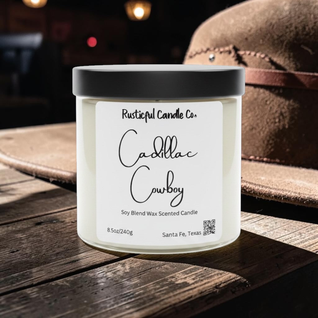 Candle jar labeled 'Cadillac Cowboy' by Rusticful Candle Co. on a wooden surface with a hat in the background.