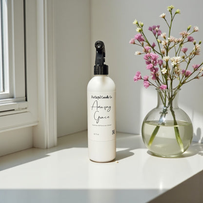 White spray bottle with black nozzle on a windowsill next to a vase with flowers
