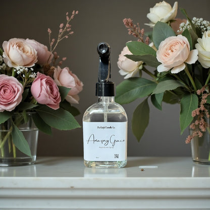 Bottle of 'Amoury Grace' with two flower arrangements in the background