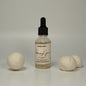 Bottle of 'Amazing Grace' with two spherical laundry balls on a neutral background