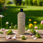 Bottle of 'Amazing Grace' soap on a wooden table with flowers and greenery in the background
