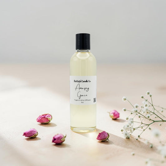 A bottle of Poshlight Candles Co. Aromatic Gaze lye soap with a black cap and white label, styled on a beige surface with pink rose buds and white baby's breath flowers.