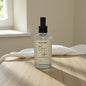 Bottle of 'Bare Skin' body mist on a wooden surface with a neutral background