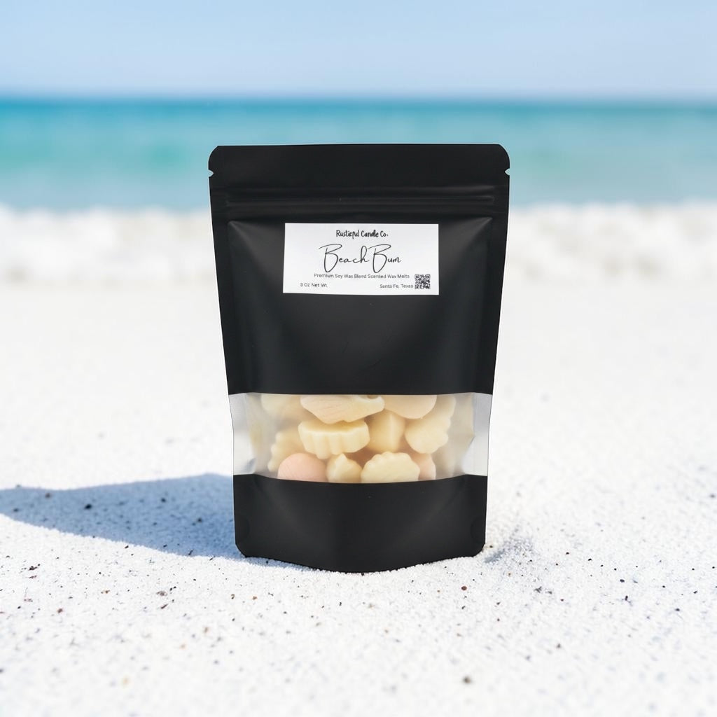 Black packaging of white chocolate chips on a sandy beach with blue sky.