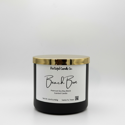 Black candle with a gold lid and 'Beach Bum' label on a white background