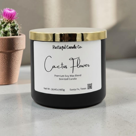 Candle labeled 'Cactus Flower' from Rusticful Candle Co. on a neutral background with a cactus plant.