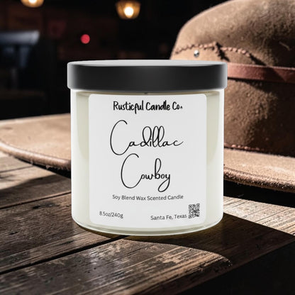 Candle jar labeled 'Cadillac Cowboy' by Rusticful Candle Co. on a wooden surface with a hat in the background.
