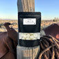 Black package with white contents on a wooden post in a desert setting