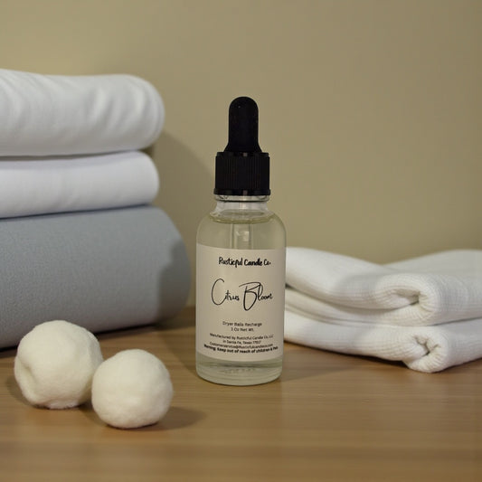 Bottle of 'Crisp Bloom' with dryer balls and folded towels on a wooden surface.