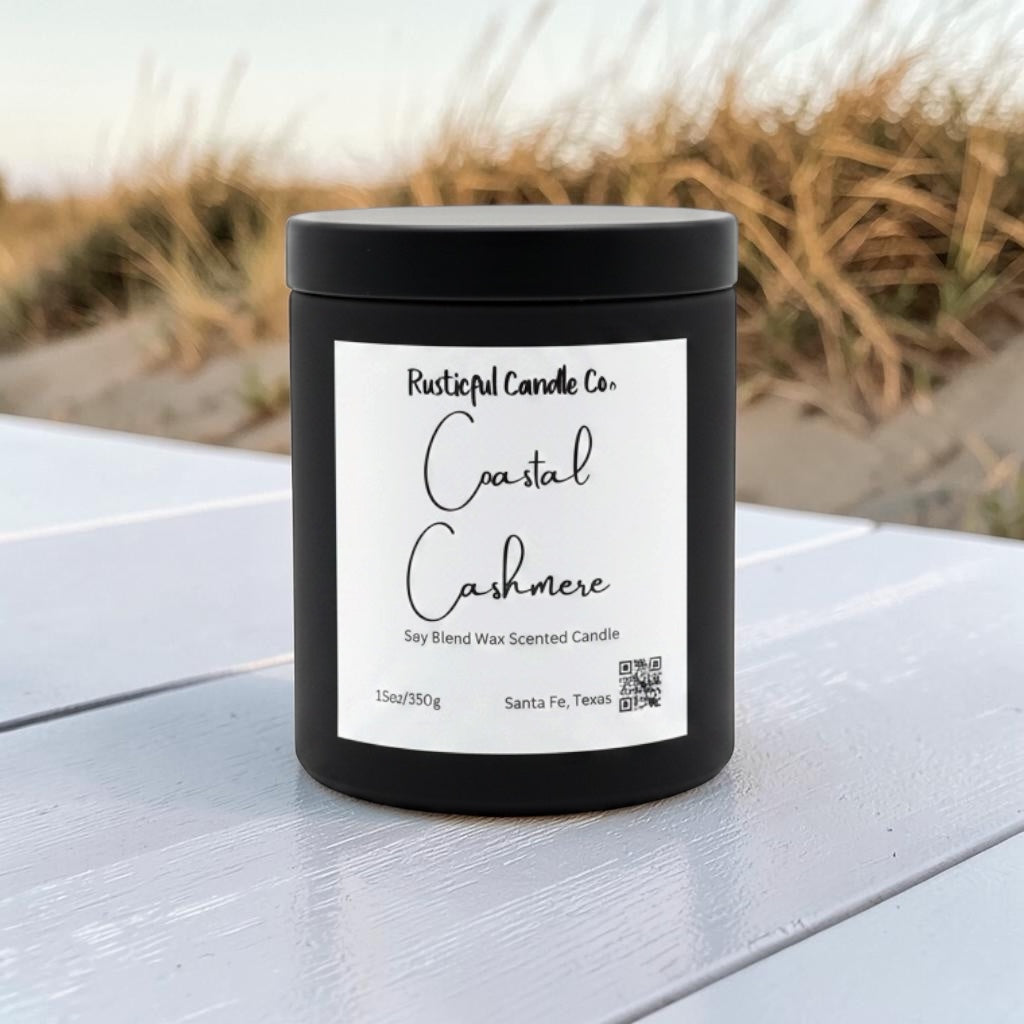 Candle on white wood surface with coastal dune grass backdrop