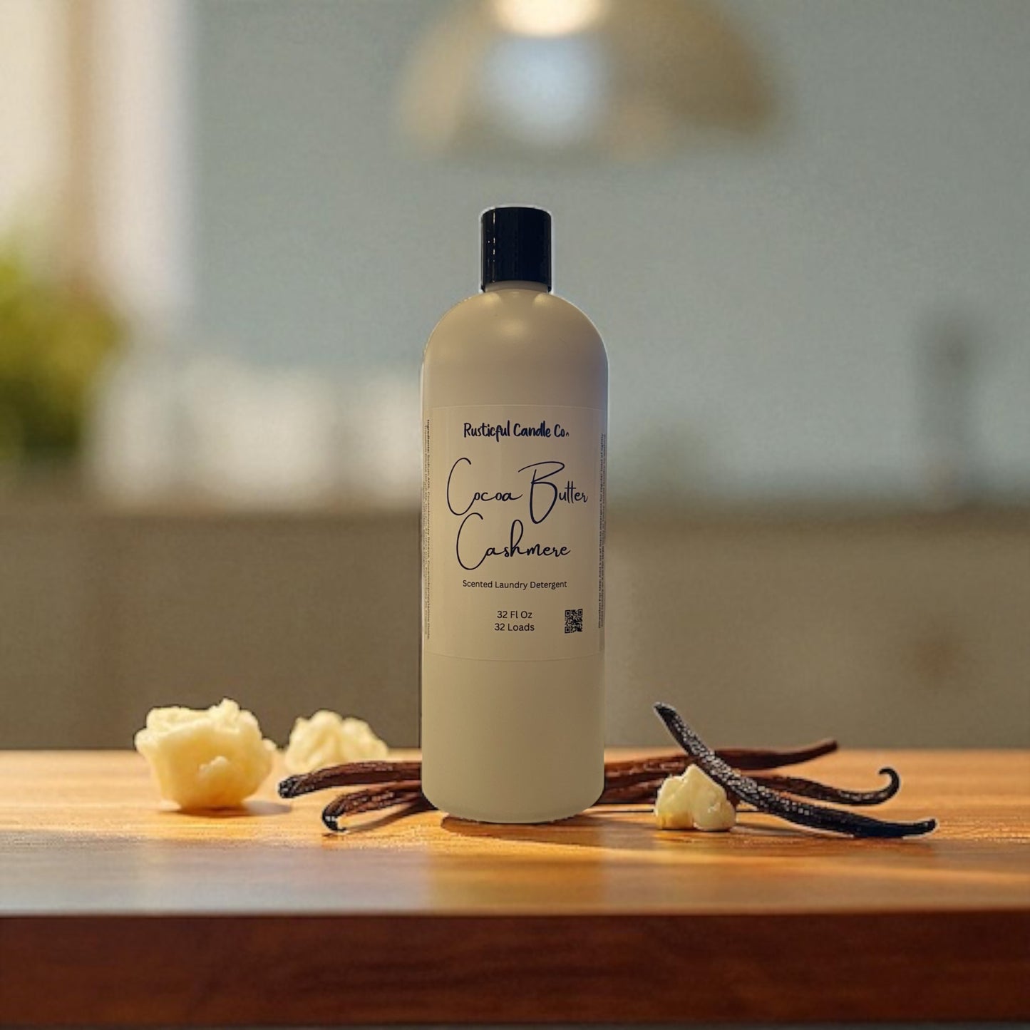 Bottle of Cocoa Butter Cashmere soap on a wooden surface with vanilla beans and flowers.