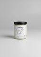 Candle jar with a black lid and white label on a gray background