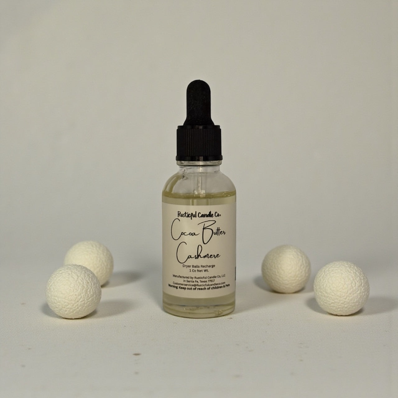 Bottle of Cacao Butter Cashmere with white balls on a gray background