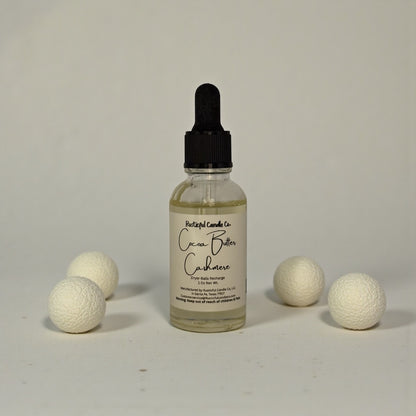 Bottle of Cacao Butter Cashmere with white balls on a gray background