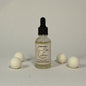 Bottle of Cacao Butter Cashmere with white balls on a gray background