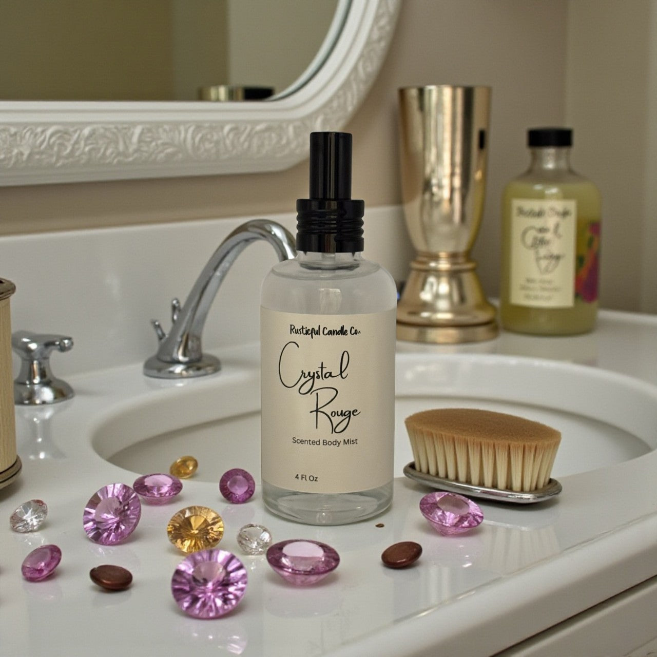 Body mist bottle labeled 'Crystal Rouge' on a bathroom counter with decorative stones and a mirror in the background.