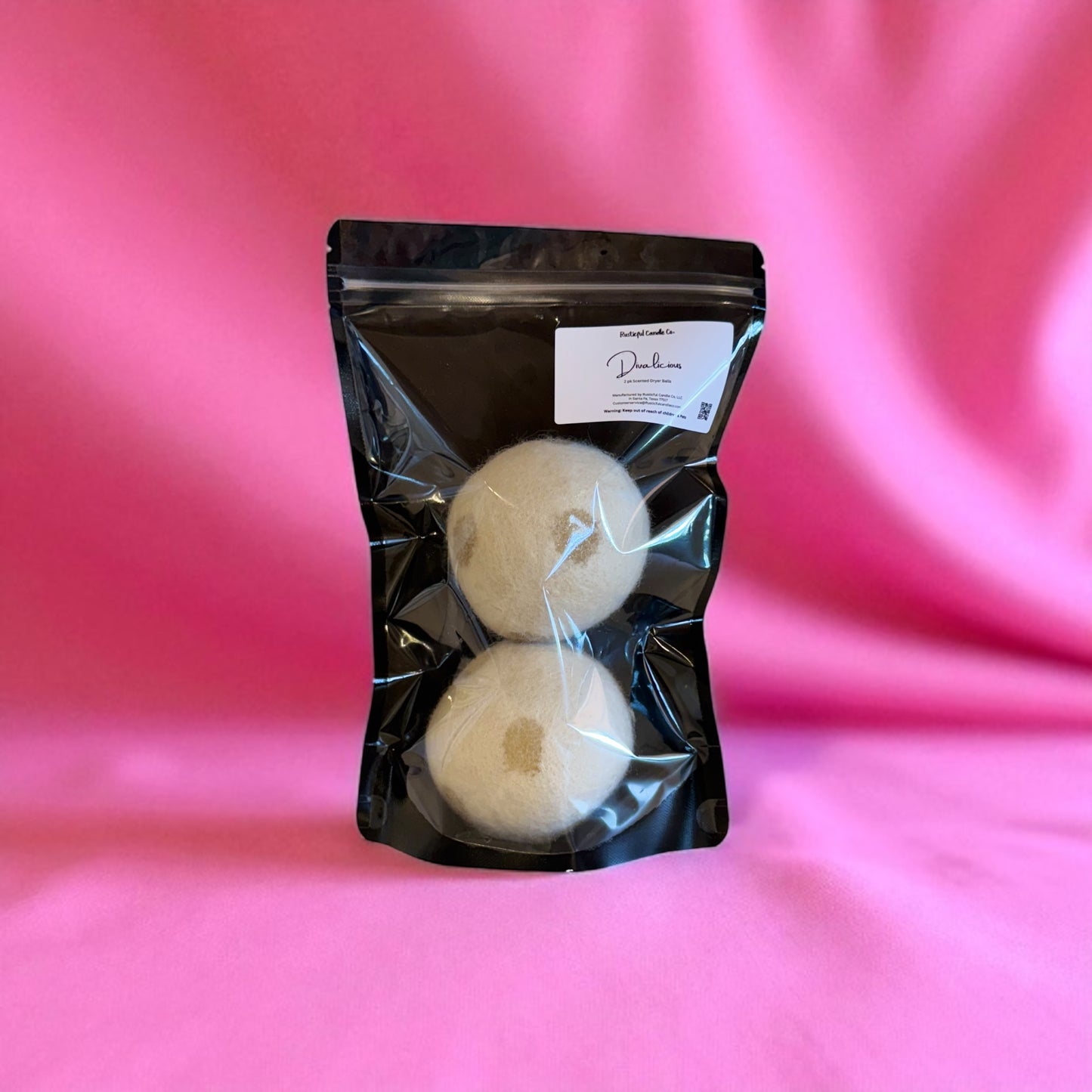 Two white circular items in a black packaging bag with a pink background