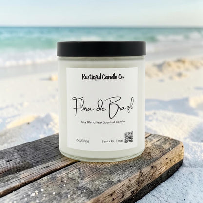 Candle labeled 'Flora de Brazil' from Rusticful Candle Co. on a beach.