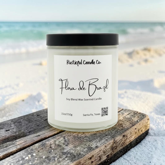 Candle labeled 'Flora de Brazil' from Rusticful Candle Co. on a beach.