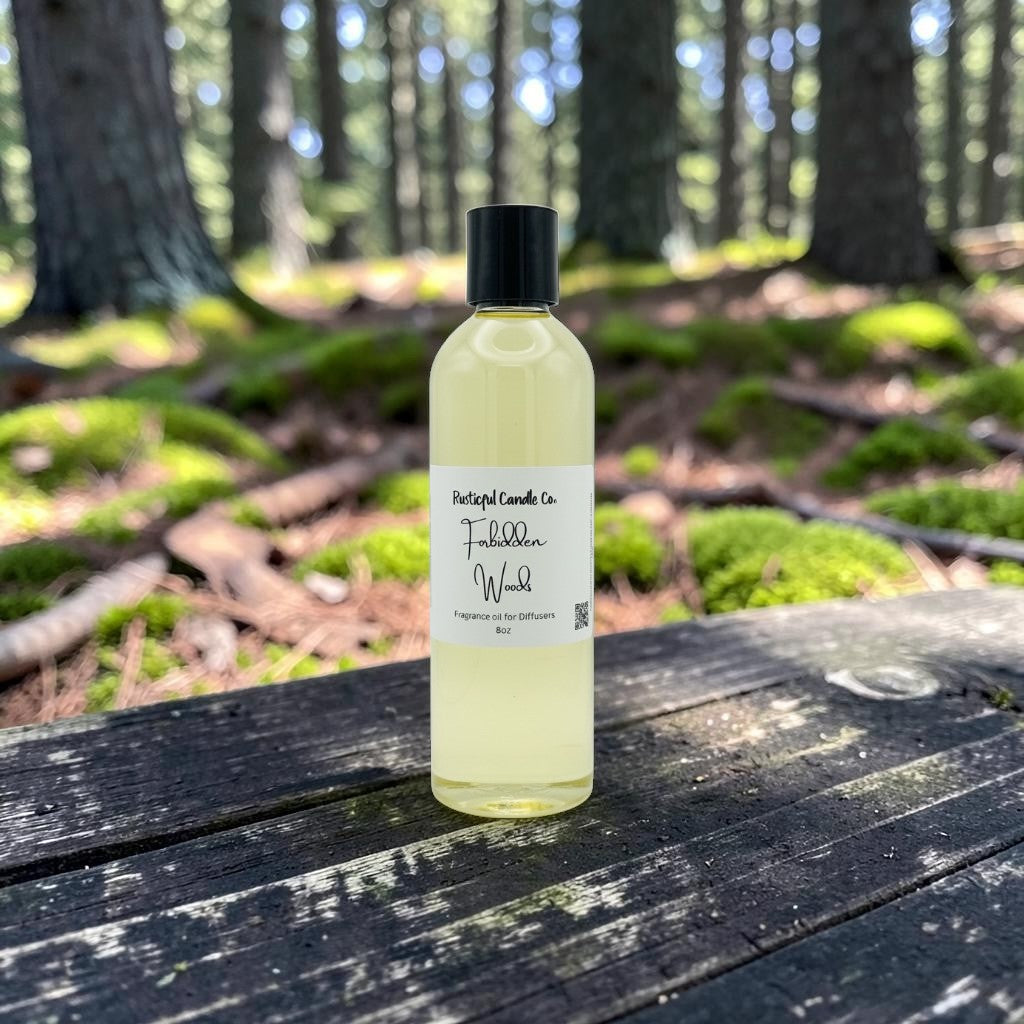 A bottle of Portugal Candle Co. Tiburon Wood fragrance oil sits on a weathered wooden table in a forest setting with mossy logs and trees in the background.