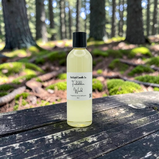 A bottle of Portugal Candle Co. Tiburon Wood fragrance oil sits on a weathered wooden table in a forest setting with mossy logs and trees in the background.