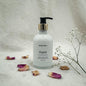 Hand lotion bottle labeled 'Gypsy' with dried flowers and a branch on a textured surface