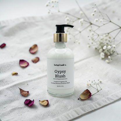 Hand lotion bottle labeled 'Gypsy Blush' on a textured surface with flowers and petals.
