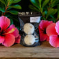 Two white bath bombs in a clear plastic bag with a black background, surrounded by pink flowers on a wooden surface.