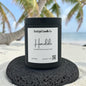 Honolulu candle on a volcanic rock with palm trees and ocean backdrop