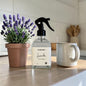 Lavender plant, spray bottle, and mug on a wooden surface