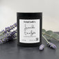 A black jar candle with a white label reading 'Lavender Eucalyptus' by Rusticful Candle Co., styled on a dark surface with lavender sprigs and eucalyptus leaves around it.