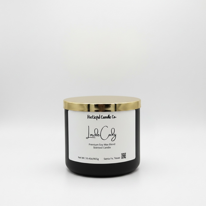 Black candle with a gold lid and white label on a light gray background