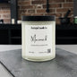 Candle labeled 'Maverick' from Rusticful Candle Co. on a dark surface with a brick wall background.