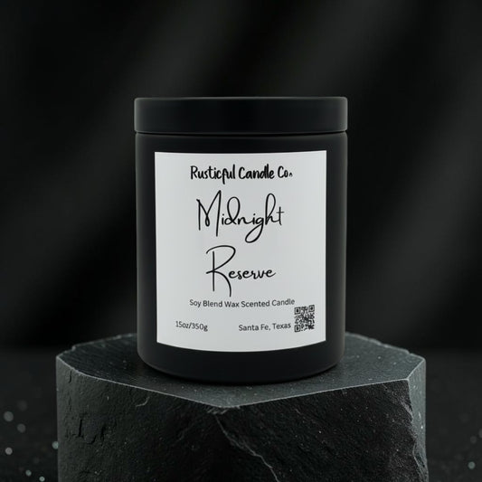 A black jar candle with a white label reading 'Rusticalful Candle Co. Midnight Reserve' sits on a dark stone pedestal against a dark blurred background.