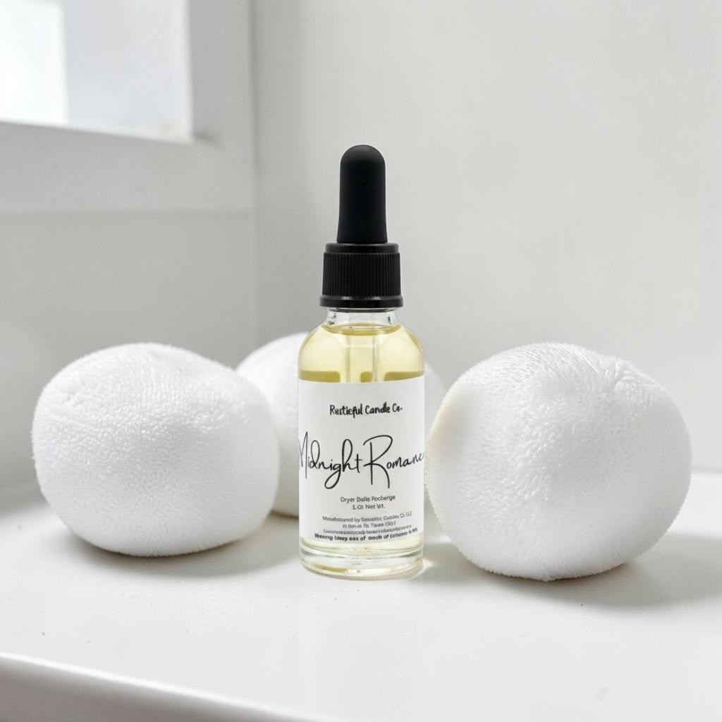 A small glass dropper bottle labeled 'Moonlight Romance' by Pretty Girl Candle Co, filled with pale yellow liquid, standing on a white surface between two white bath bombs against a bright white background.