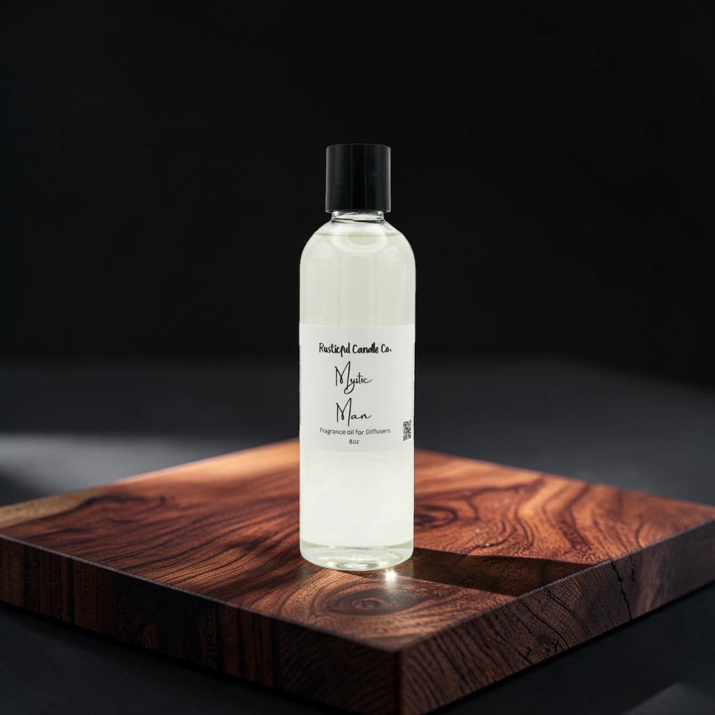 A clear glass bottle of fragrance oil with a black cap and a white label reading 'Pastel Candle Co. Myke Man', standing on a dark wooden board against a black background.