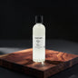 A clear glass bottle of fragrance oil with a black cap and a white label reading 'Pastel Candle Co. Myke Man', standing on a dark wooden board against a black background.