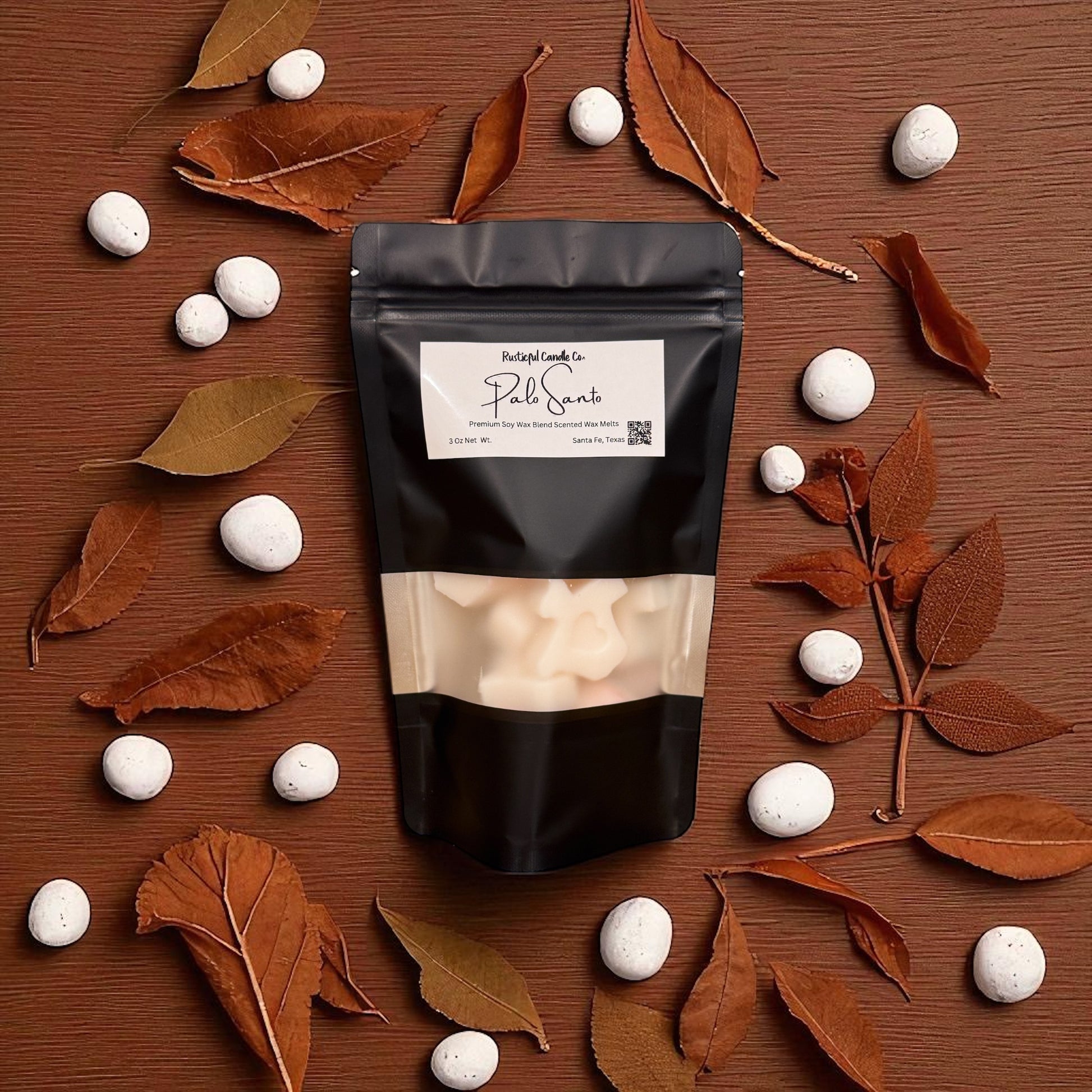 Black packaging with a label on a wooden surface with white stones and brown leaves.