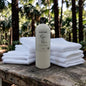 Bottle of 'Mythic Man' product with folded towels on a wooden surface outdoors.