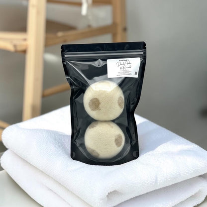 Two laundry detergent balls in a clear plastic bag on a white towel with a blurred background