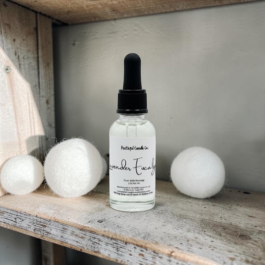 Bottle of lavender essential oil with dropper on a wooden shelf with cotton balls.
