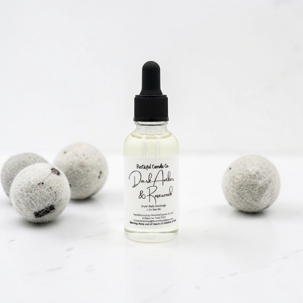 Bottle of 'Dark Amber & Rosewood' scented oil with dryer balls on a white background