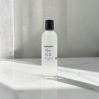 A clear cylindrical bottle of fragrance oil with a black cap and a white label reading 'Pleasant Candle Co. Romeo No.
