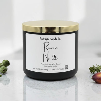 A black jar candle with a shiny gold lid and a white label reading 'Rustical Candle Co. Reverie No.