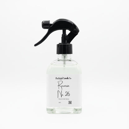A clear glass spray bottle with a black trigger sprayer and a white label reading 'Pleasant Candle Co. Reverse No.