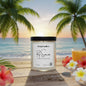 Candle labeled 'Rio Sunrise' from Rustful Candle Co. on a beach setting with palm trees and flowers.
