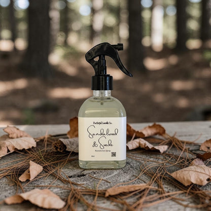 Bottle of candle wax and suede cleaner with a label on a wooden surface with leaves and twigs, blurred forest background