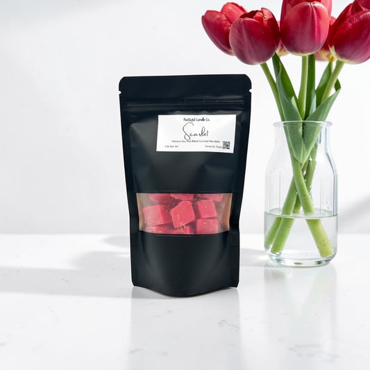 Black pouch with transparent window displaying red cubes next to a vase of red tulips on a white background