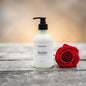 White bottle labeled 'Scarlet' with a red rose on a wooden surface