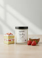 Candle labeled 'Strawberry Cake' with a small cake and strawberries on a light background